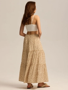 Detail of high waisted tiered floral skirt and pleated crop top with side view drape