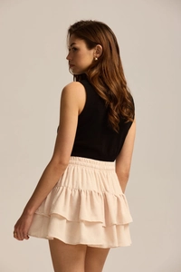 Detail view showing tiered ruffles and elastic waist of the beige mini sports skirt