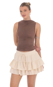 Detail of high waist ruffled mini skirt with adjustable drawstring and brown tank top