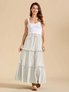 Détail d'un crop top blanc en maille torsadée et d'une jupe longue à volants crème