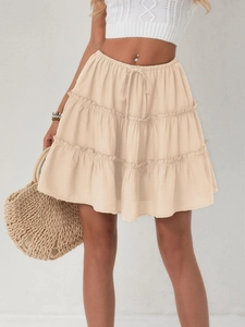 Detail of adjustable drawstring waistband and tiered ruffle layers on beige mini skirt