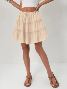 Detail view of beige tiered high-waisted mini skirt with adjustable drawstring ties