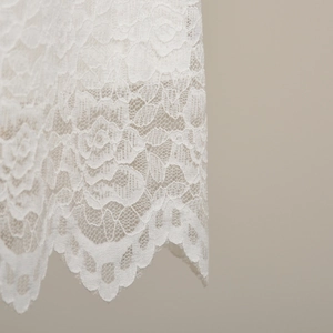 Détail d'ourlet en dentelle florale blanche avec broderie ajourée et bords festonnés