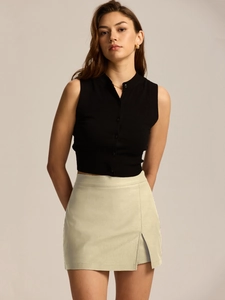 Detail view of high waist skirt with side slit and black sleeveless polo top