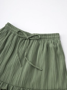 Détail de la taille haute élastique avec cordon et texture plissée sur la jupe verte