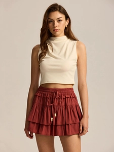 Detail showing high-waisted tiered skort with drawstring and cream ribbed sleeveless crop top