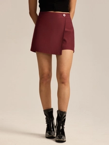 Detail view of burgundy wrap mini skirt with asymmetrical hem and matching waist button