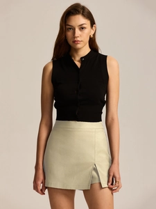 Detail shot of black sleeveless knit top with high-waist side slit beige mini skirt