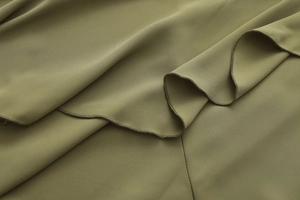 Detail of olive green chiffon fabric with ruffle hem and high-quality overlock stitching