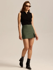 Close-up of high-waist split hem dark green skirt with chic black sleeveless knit vest