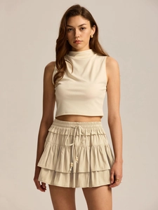 Close-up detail of tiered ruffles and adjustable drawstring with wood beads on off-white skort