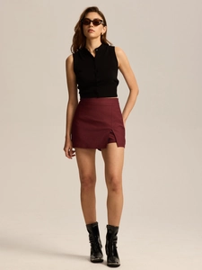 Detail of high waisted burgundy skort with asymmetric slit and black knitted sleeveless top