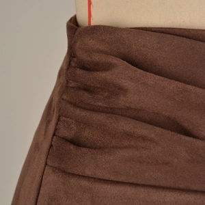 Close-up of ruched dark brown faux suede fabric with elegant pleated texture on a skort