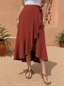 Detail showing the layered ruffles and high-waist tie of this terracotta wrap midi skirt