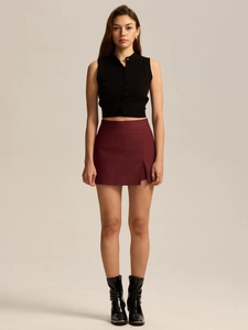 Detail of high waist burgundy mini skirt with a side slit and black sleeveless cardigan