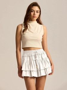Detail of white tiered skort featuring elastic waist and decorative drawstrings with beads