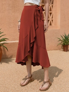 Close-up detail of terracotta wrap skirt featuring ruffle hem and adjustable waist tie