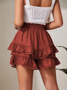 Detailed back view of layered rust-red ruffle shorts with delicate white crochet lace trim