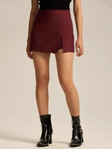Detail of burgundy high-waisted skort featuring a side slit and textured woven fabric