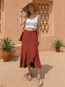 Detail of rust red wrap midi skirt featuring a ruffled hemline and high waist tie closure