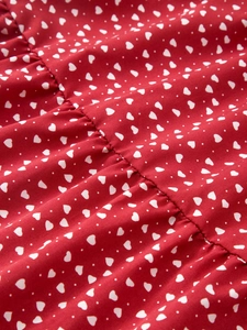 Détail d'une jupe en coton rouge avec imprimés cœurs blancs et texture de tissu plissée