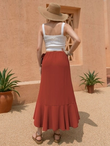 Back view of a woman wearing a white knit top and a rust red ruffled bohemian wrap skirt