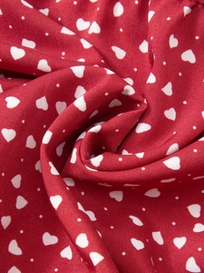 Gros plan du tissu de jupe en coton rouge avec imprimé cœurs blancs et petits pois