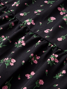 Détails d'une jupe en coton à imprimé fleuri avec roses roses sur tissu noir et plis fins