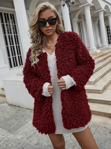 Détail de la texture d'un manteau bordeaux en fausse fourrure et colliers dorés