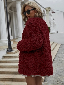 Gros plan sur la texture en fausse fourrure d'une veste courte chic rouge vin pour femme
