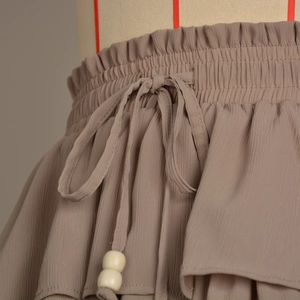 Detail of the elastic waistband with drawstring and cream beaded ends on a layered skirt