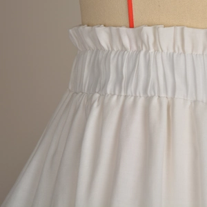 Close-up of the elastic ruffled waistline on the white layered tiered mini skirt