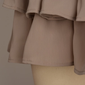 Detail shot of multi-layer ruffled hem in mocha chiffon fabric with fine stitching