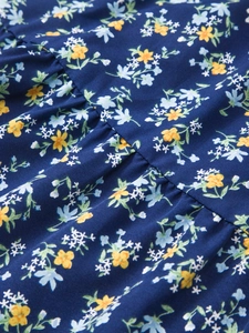 Détail du tissu en coton bleu foncé de la jupe à fleurs montrant les plis et motifs