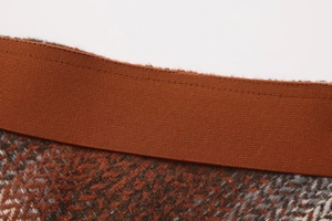 Detail view of high elastic waistband and retro plaid tweed fabric on a winter skirt