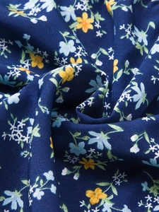 Vue macro détaillée du tissu en coton bleu foncé avec de petits imprimés floraux colorés