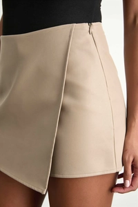 Detail of high waist beige faux leather wrap skort showing side zipper and fine stitching