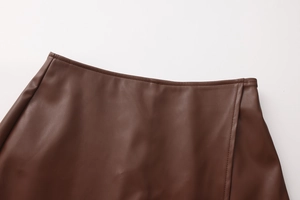 Detail of high-waist brown PU leather skirt featuring precise stitching and smooth texture