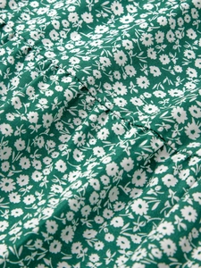 Gros plan sur tissu en coton vert à fleurs avec imprimé marguerites blanches et détails plissés