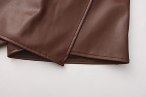 Detailed close-up showing double-needle stitching on dark brown PU leather skirt