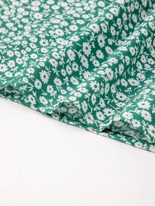 Détail macro du tissu en coton vert foncé avec fleurs blanches et coutures lisses