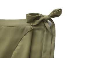 Detail of olive green wrap skirt showing the elegant waist tie bow and textured fabric
