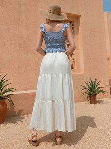 Dettaglio di gonna lunga a balze in cotone e lino bianco con crop top a fiori estivo