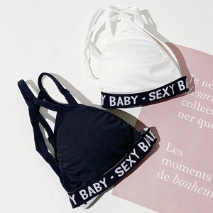 Detail of cross-back straps and branded elastic band on black and white sports bras