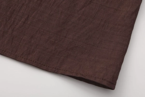 Détail de couture sur l'ourlet d'une jupe longue en coton et lin marron texturé