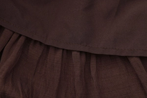 Gros plan détaillé d'une jupe en coton marron foncé avec plis fins et coutures nettes
