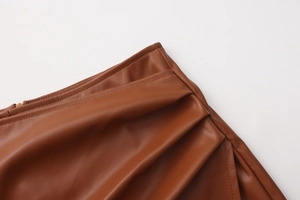 Detail of high waist pleated brown faux leather skirt pants with textured stitching