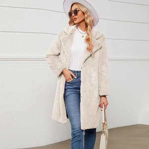 Gros plan sur la texture en fausse fourrure et les revers larges de ce long manteau ivoire