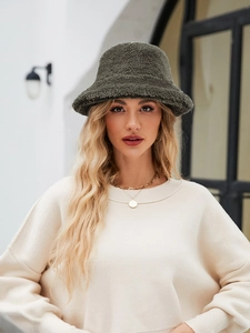 Detailaufnahme des olivgrünen Lammfell-Anglerhuts kombiniert mit einem beigen Strickpullover