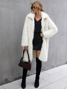 Detail of a plush white faux fur coat featuring a classic lapel collar and long sleeves